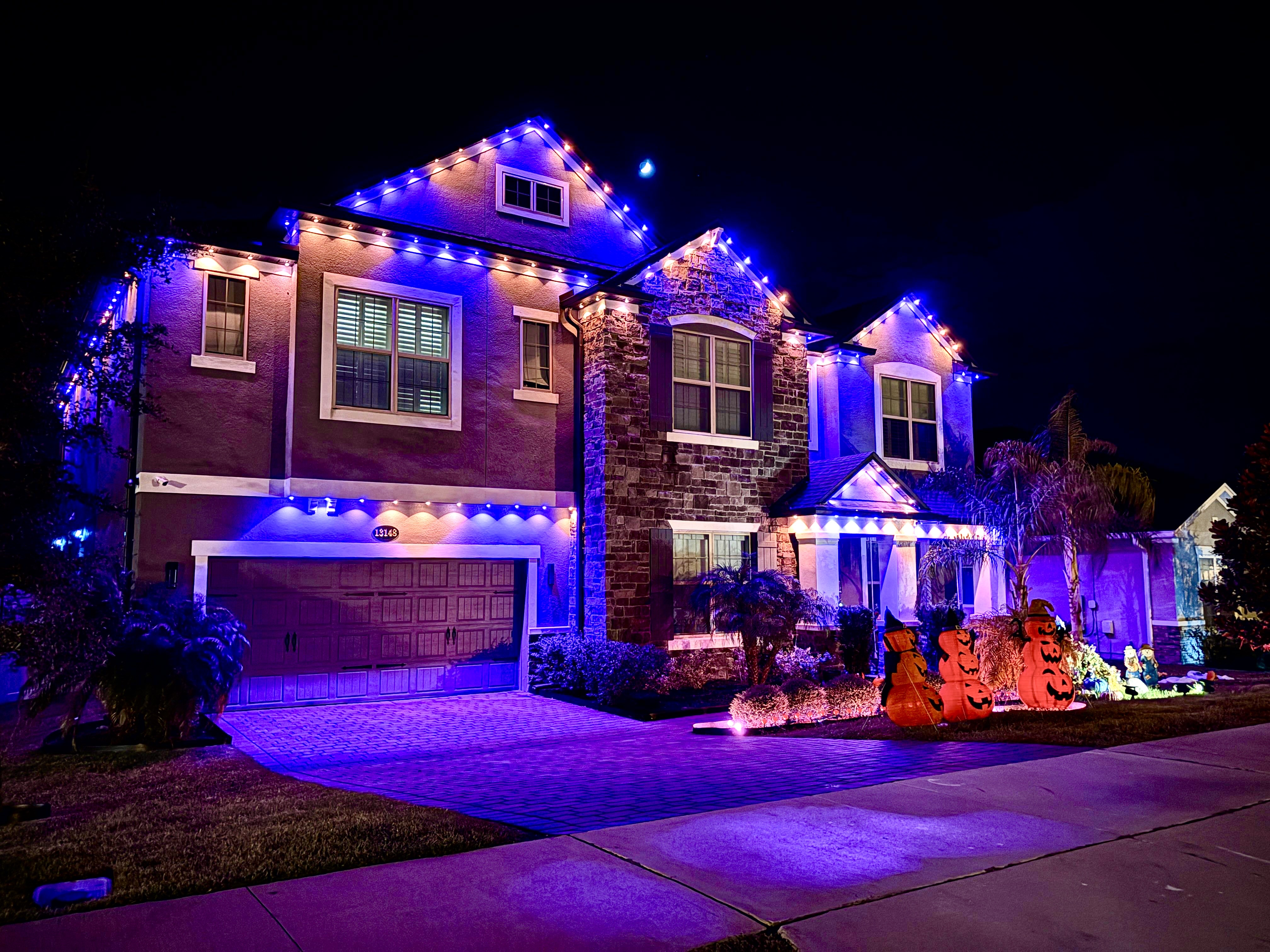 Purple and pink LED permanent Christmas lighting on house with Halloween decorations
