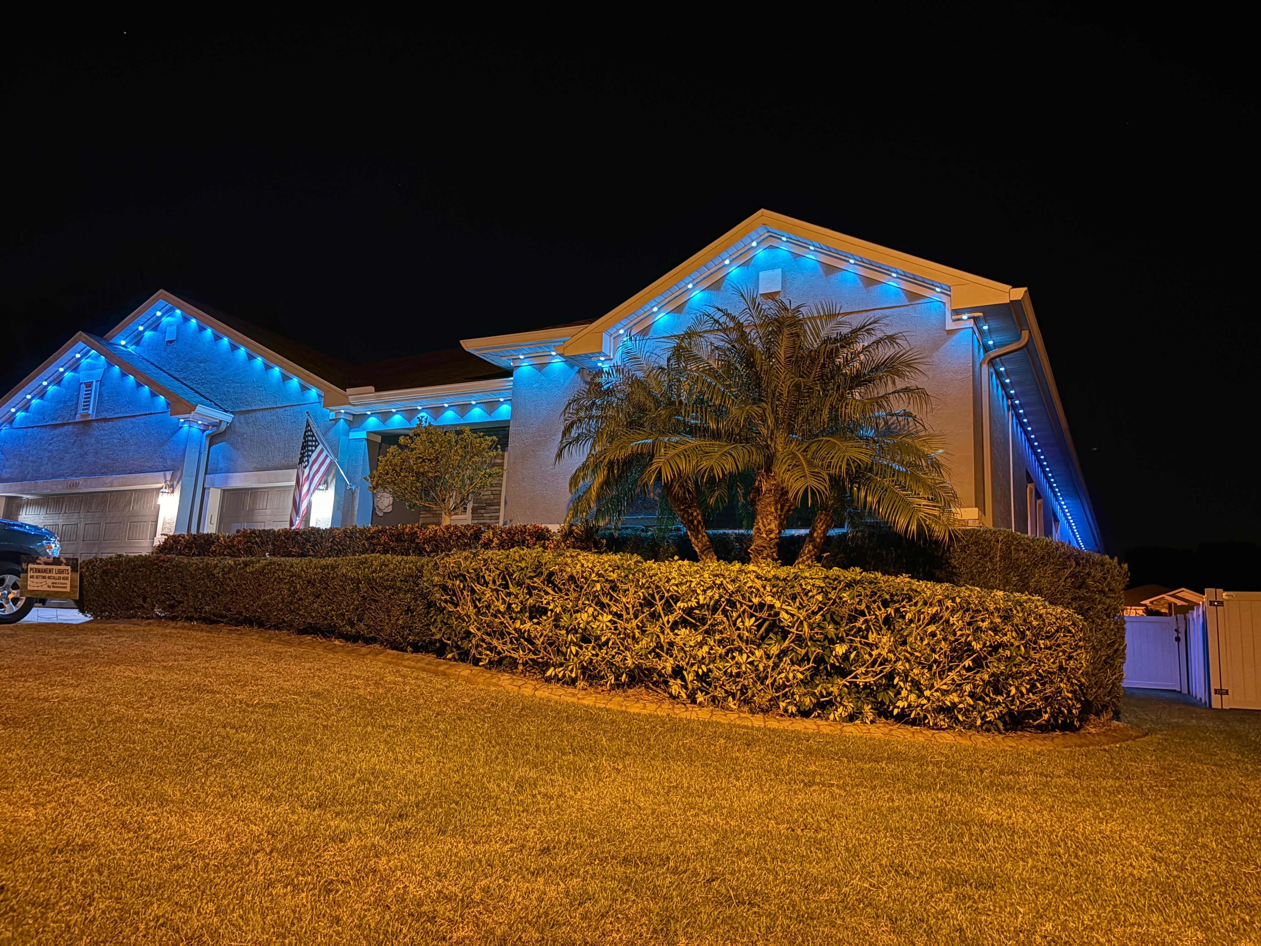Bright blue permanent Christmas lighting on house with palm trees
